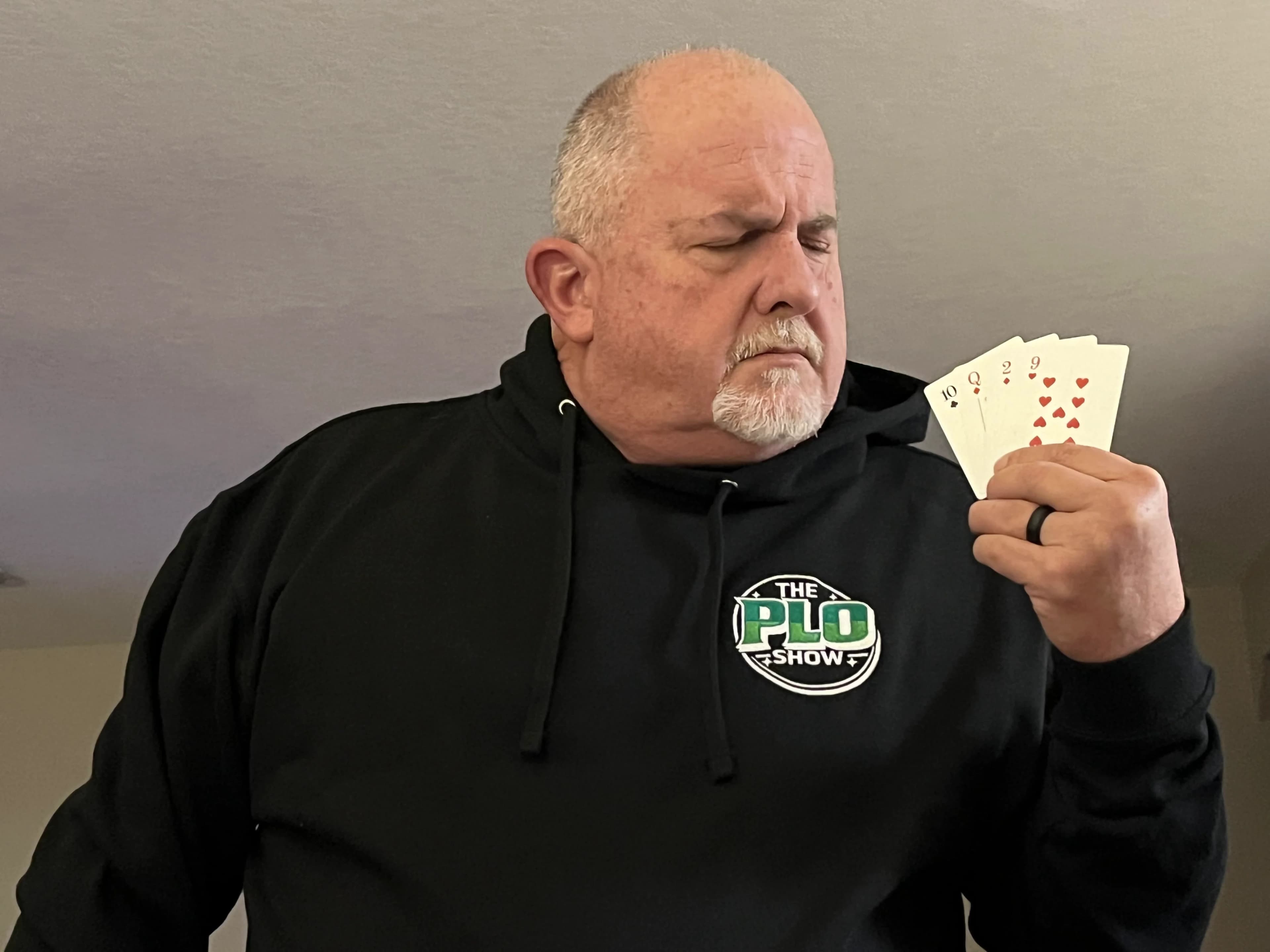 PLO Show fan in the black hoodie studying his hand of cards