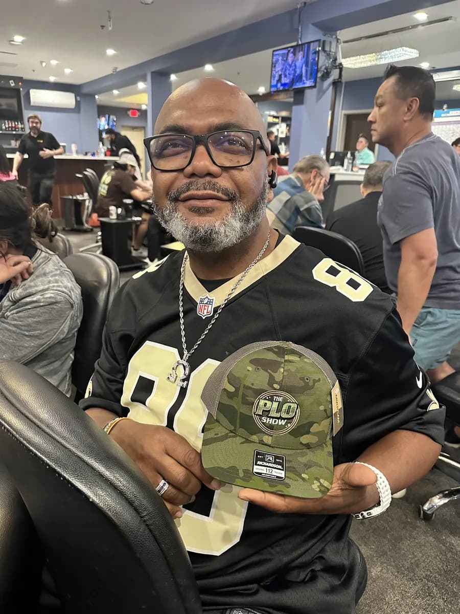 PLO Show fan holding the Multicam trucker hat at the poker room